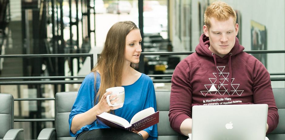 Eine Studentin und ein Student blicken gemeinsam in einen Laptop.