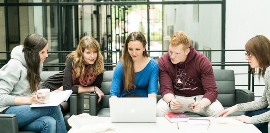 Studierende an einem Tisch mit Laptop