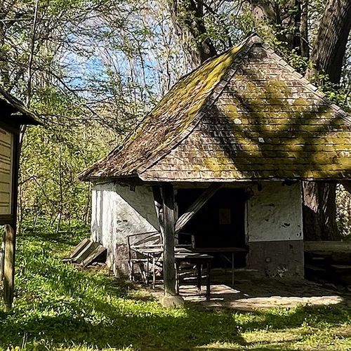 Orte des Rechts: Kleine Hütte im Grünen. Davor zu sehen eine Informationstafel..