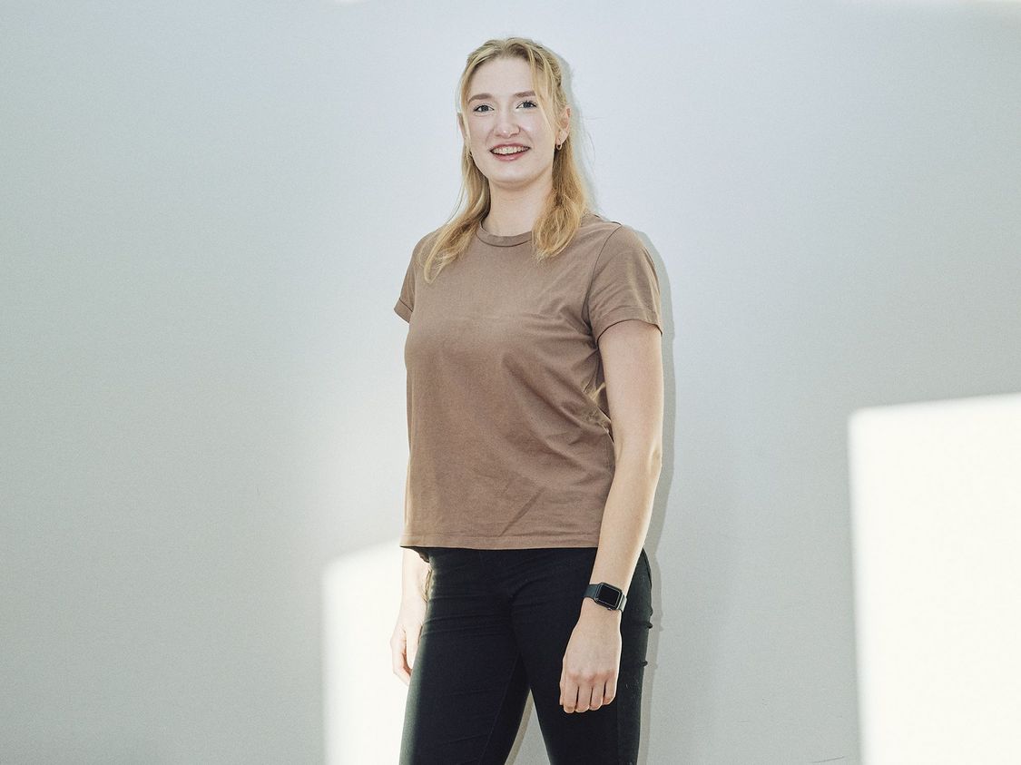 Alumna des Masterstudiengangs Public Management vor weißer Wand mit Lichtreflex