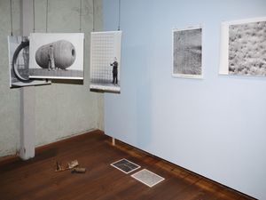 Ansicht eines Raumes mit frei im Raum hängenden Bildern, Bildern an der Wand und dem Boden.
