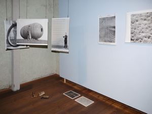 Ansicht eines Raumes mit frei im Raum hängenden Bildern, Bildern an der Wand und dem Boden.