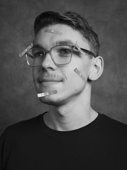 Männliche Person mit Brille und Zetteln im Gesicht.