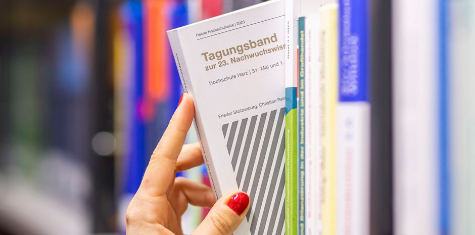 Eine Hand greift ein Buch aus einem Regal