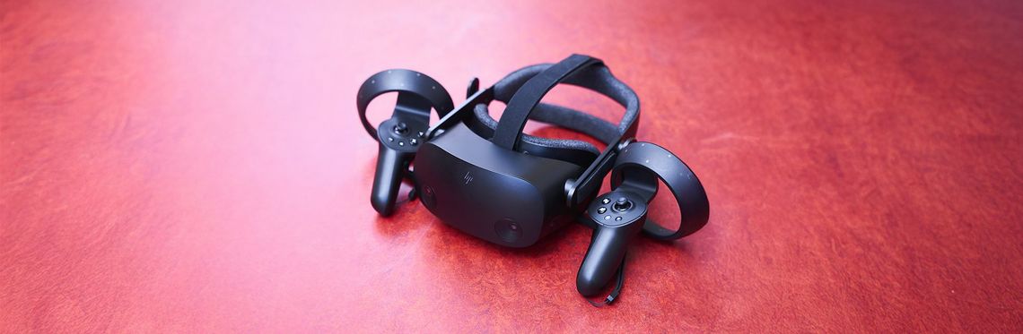VR-Brille und zwei Controller vor rotem Hintergrund