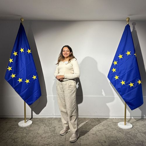 Frau steht zwischen zwei EU-Flaggen