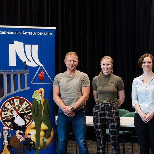 Gruppenbild von Studierenden der Hochschule Harz und Mitarbeitenden des Nordharzer Städtebundtheaters beim Pressetermin vor schwarzem Hintergrund