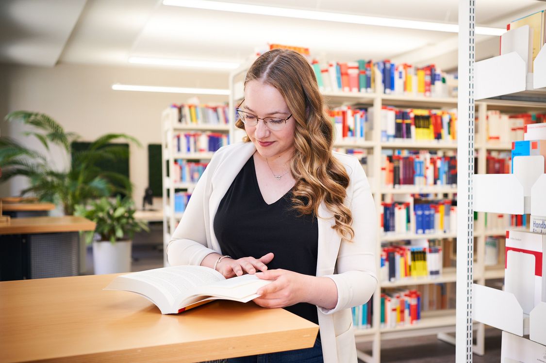 Studierende der Öffentlichen Verwaltung der Hochschule Harz mit einem Buch in der Bibliothek
