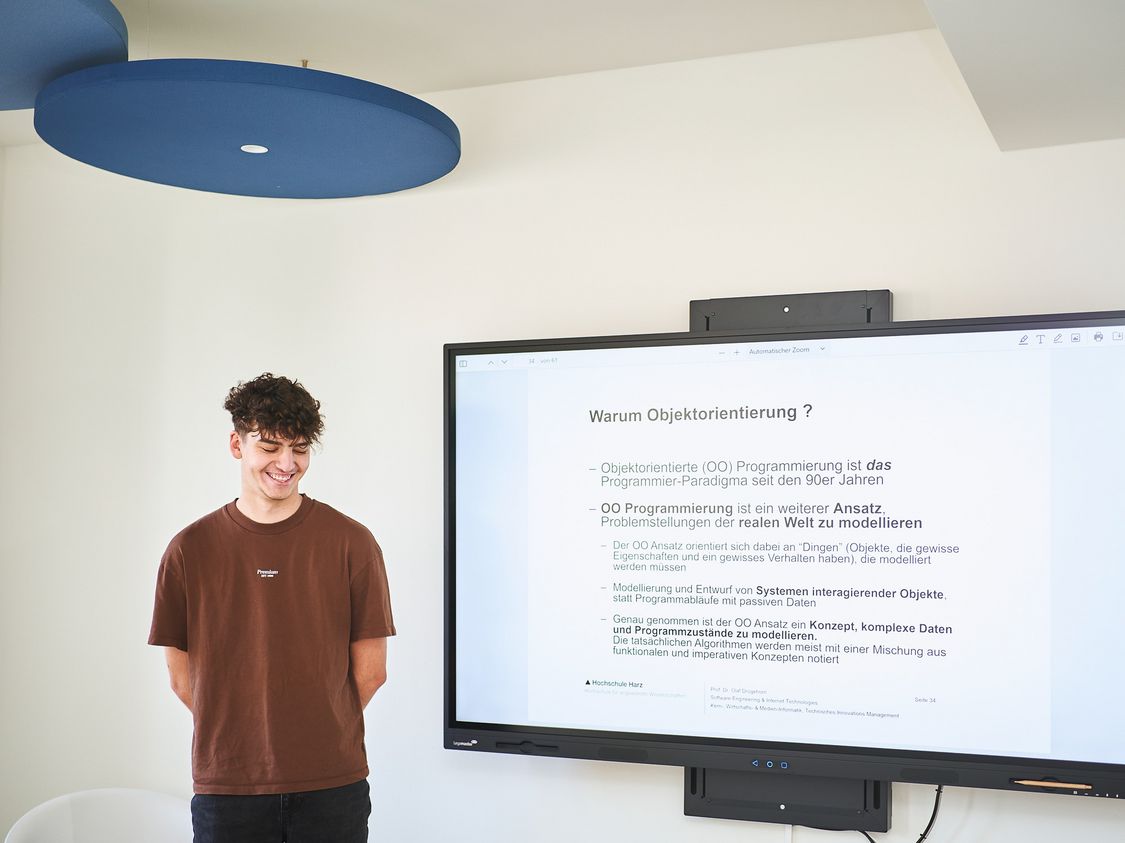 Ein Studierender des IT-Managements –  Verwaltungsinformatik vor einem digitalen Whiteboard in einem neu eingerichteten Lernort.