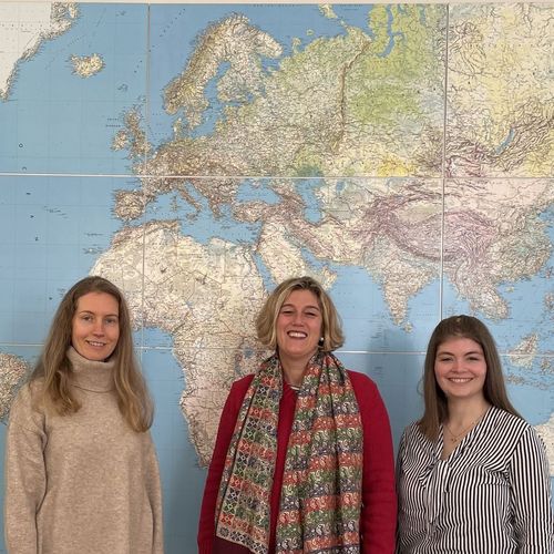 Bild mit drei Frauen vor einer Weltkarte zeigt das Team der "International Research Week" der Hochschule Harz