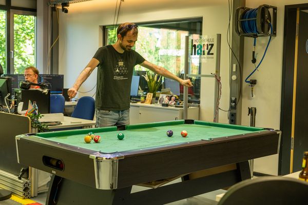 Mann breitet Arme über Billiardtisch aus